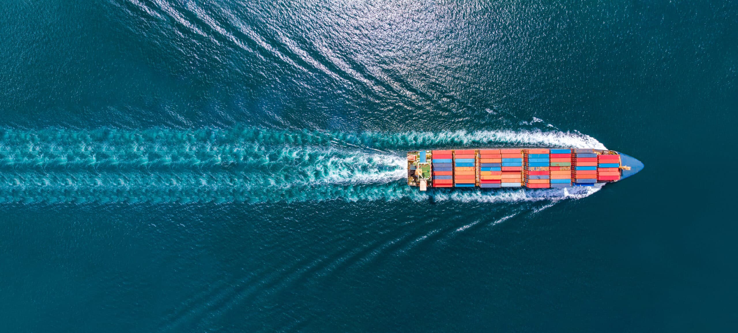 Aerial top view of cargo ship with contrail in the ocean sea shi